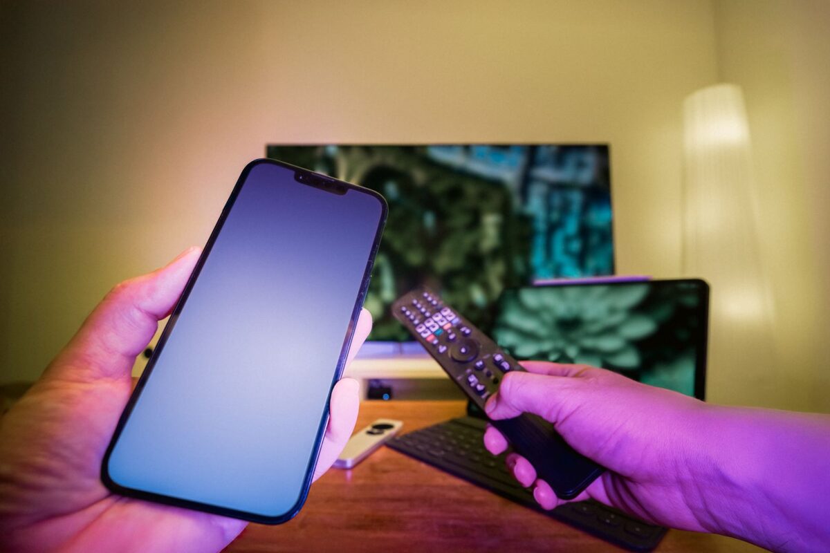 Smartphone et télécommande devant un téléviseur connecté diffusant du streaming